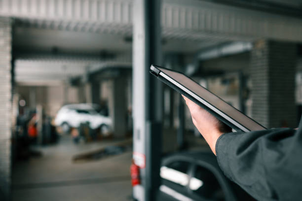 مکانیک متخصص در حال بررسی عیبیابی خودرو با تبلت در یک تعمیرگاه مدرن