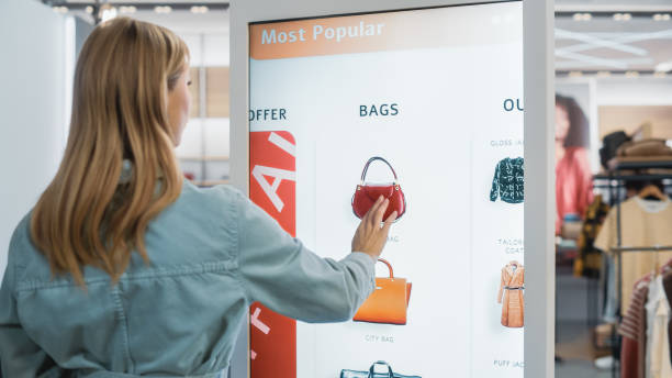 مشتری در حال تعامل با یک نمایشگر هوشمند در فروشگاه که نمونه‌ای از تجربه کاربری مدرن است.