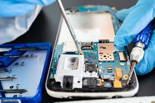 تعمیرکار موبایل در حال کار روی برد گوشی با ابزار دقیق