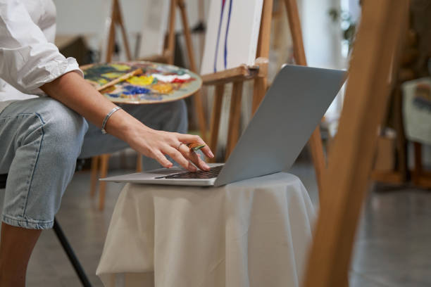 یک مجموعهدار در حال بررسی و خرید آنلاین آثار هنری با لپتاپ از یک وبسایت فروشگاهی هنری ساخته شده با وردپرس و ووکامرس.