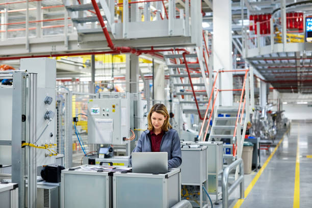 کاربرد فناوری در کارخانه مهندس در خودور در حال استفاده از لپ تاپ در کارخانه