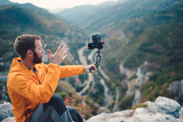بلاگر سفر در حال ولاگ گرفتن در قله کوه برای تولید محتوای ویدیویی