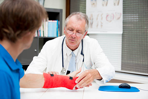 پزشک متخصص ارتوپدی در حال معاینه دقیق شکستگی بازوی بیمار در کلینیک