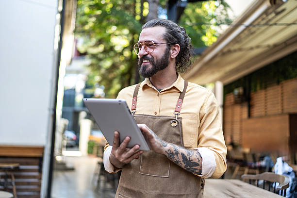 یک باریستا در حال کار با تبلت برای ثبت سفارش یا رزرو مشتریان در کافه - تحول دیجیتال رستوران
