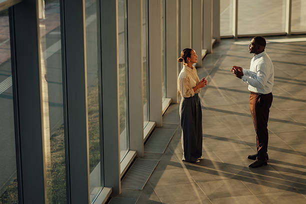 گروهی از افراد در حال بحث و گفتگو در یک ساختمان اداری مدرن، نشاندهنده برندینگ دیجیتال موفق دفاتر معماری - برندینگ دیجیتال معماری، طراحی وبسایت، وبسایت دفاتر معماری