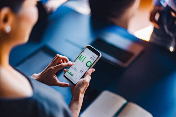 زنی در حال تحلیل دادهها با گوشی هوشمند در دفتر کار، نمادی از بازاریابی دیجیتال، تحلیل استراتژی تبلیغاتی نوین و جذب مشتری آژانسهای تبلیغاتی