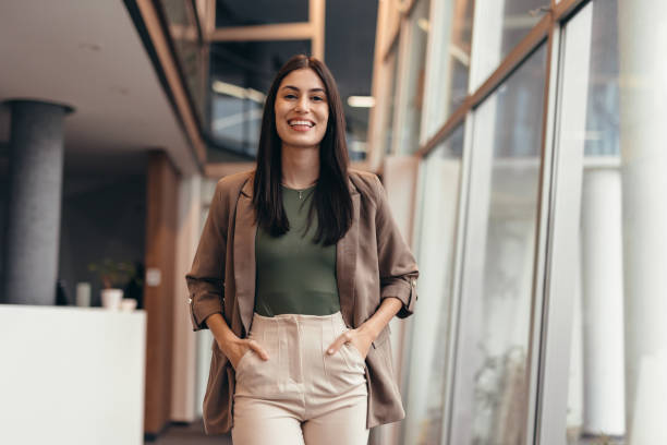 زنی با اعتماد به نفس در حال قدم زدن در یک ساختمان اداری مدرن، نمادی از موفقیت در معماری لبخند دیجیتال و سئو محلی برای کلینیکهای دندانپزشکی اهواز