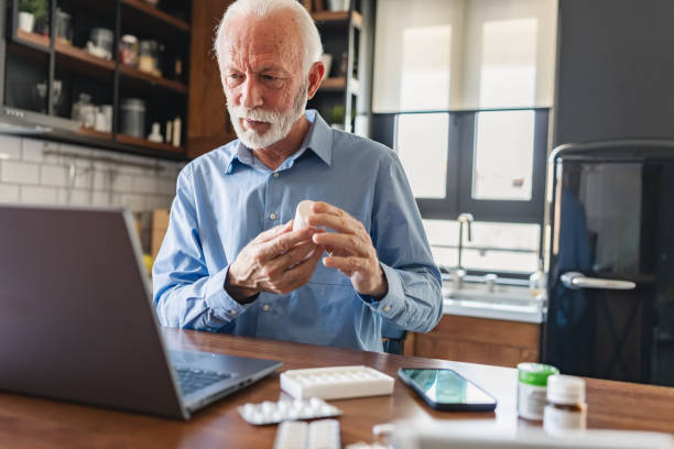 مرد مسن در خانه با لپتاپ و قرصهای مختلف، نمادی از سلامت دیجیتال و داروخانه آنلاین - استراتژی طراحی سایت PWA و سئو فوق محلی برای صدرنشینی داروخانهها در کرج