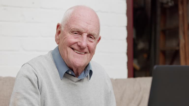 یک مرد سالمند در حال استفاده از لپتاپ، نشاندهنده دسترسی سالمندان و خانوادهها به اطلاعات از طریق وبسایت و سئو جستجوی صوتی