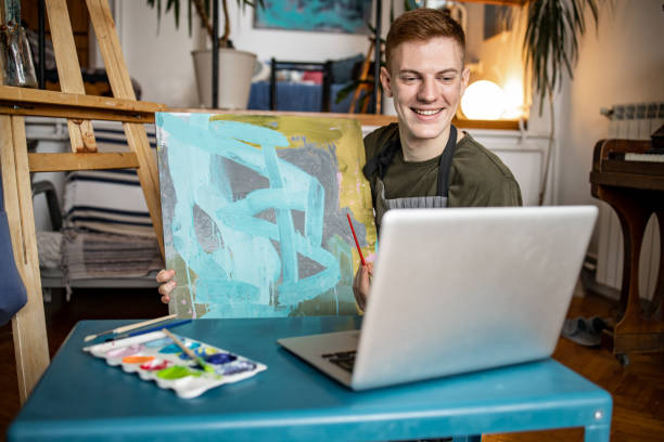 هنرمند جوان در حال نمایش کار جدید خود در تماس تصویری، نمادی از ارتباط آنلاین و جذب هنرمندان از طریق پلتفرمهای دیجیتال