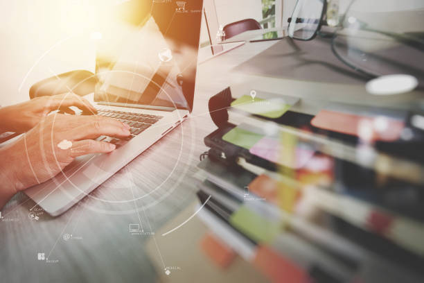 یک تاجر با آیکونهای مجازی روی میز چوبی مدرن دفتر، موبایل و دیجیتال، استراتژی دیجیتال نشر، پلتفرم دیجیتال ناشران، طراحی وبسایت