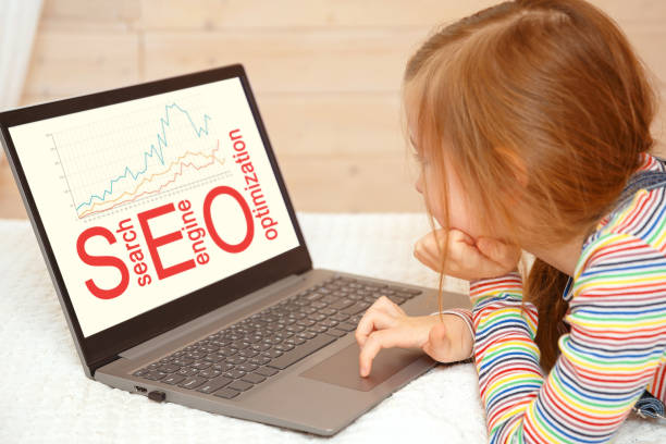 دختر کوچکی در حال نگاه کردن به کامپیوتر و نمایش کلمات کلیدی سئو در مشهد: طراحی سایت مهدکودک و جلب اعتماد والدین آنلاین