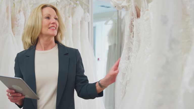 برندینگ دیجیتال مزون عروس - صاحب مزون لباس عروس در حال بررسی لباسها با تبلت دیجیتال