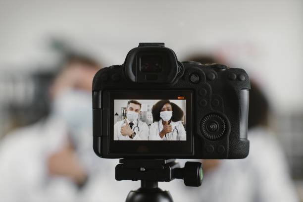 تیم پزشکی چند نژادی با ماسک در حال ضبط ولاگ. تولید محتوای ویدئویی پزشکی، برندینگ دیجیتال پوست و مو