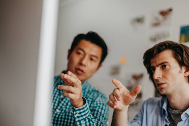 همکاران خلاق در دفتر کار در کنار کامپیوتر در حال همکاری - تجسم خانههای رویایی در شیراز: نقش کلیدی بهینهسازی تجربه کاربری (UX) و تور مجازی در طراحی سایت دفاتر معماری داخلی