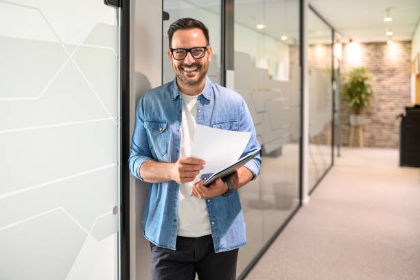 تصویر یک برنامهنویس با اعتماد به نفس در حال کار با لپتاپ و مدارک، نمادی از تخصص و دیجیتال مارکتینگ برای شرکتهای فنی