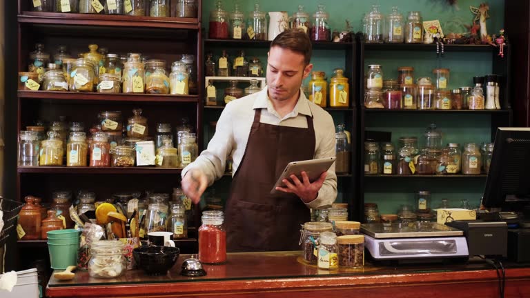 صاحب عطاری در حال بررسی موجودی محصولات خود با تبلت، نمادی از دیجیتالی شدن عطاریها و استراتژی دیجیتال مارکتینگ