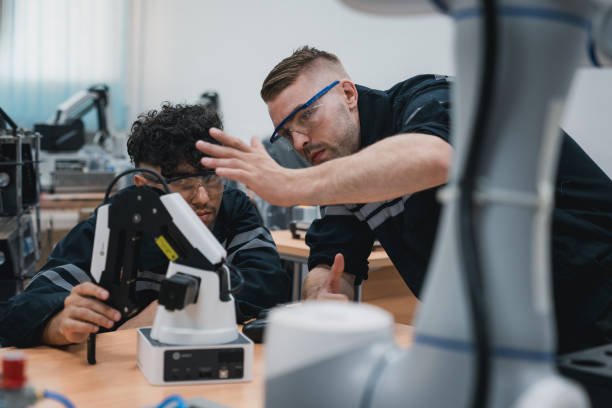 مسیر شغلی هوشمند در اصفهان ۱۴۰۵: دانشجوی مهندسی در حال مونتاژ بازوی رباتیک با کامپیوتر در کارگاه فناوری، نمادی از آموزش با هوش مصنوعی و مسیر شغلی هوشمند