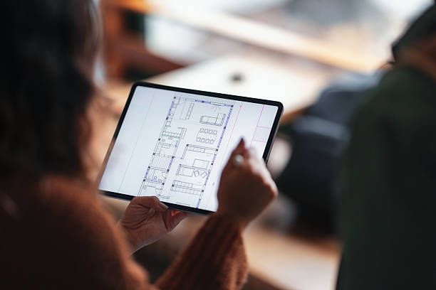 دانشجویی که در کافی شاپ به نقشه معماری در تبلت نگاه میکند - تجسم خانههای رویایی در شیراز: نقش کلیدی بهینهسازی تجربه کاربری (UX) و تور مجازی در طراحی سایت دفاتر معماری داخلی