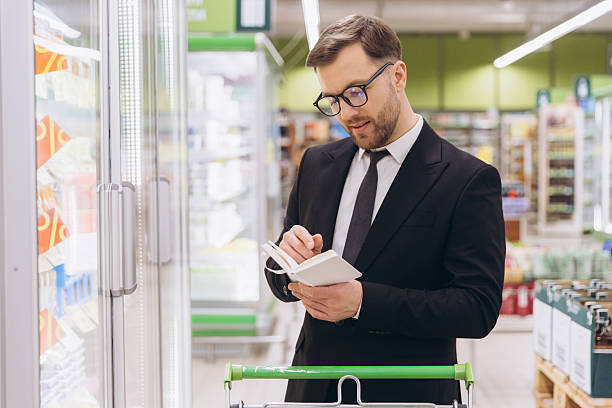 مدیر سوپرمارکت در حال بررسی کالاهای یخچالی - مدیریت تازگی محصول و تضمین کیفیت