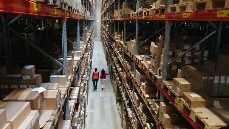تصویر دو کارگر انبار در حال حرکت در انبار، نمادی از عملیات لجستیک و مدیریت حملونقل بینالمللی