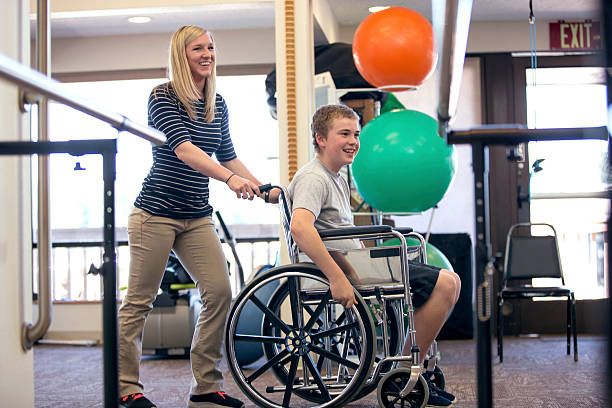 تصویر فیزیوتراپیست زن در حال هل دادن پسر نوجوان با ویلچر در مرکز توانبخشی ارومیه - توانبخشی جسمی، پایداری داده وبسایت