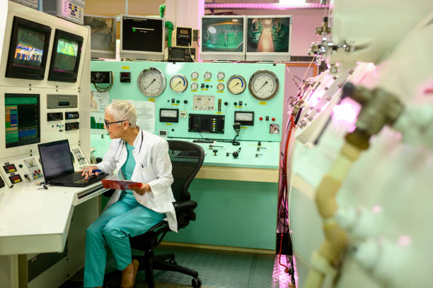 طراحی سایت پزشکی و برندینگ دیجیتال مراکز پزشکی هستهای در مشهد: پزشک در حال بررسی دادههای پزشکی بیماران روی لپتاپ در یک اتاق کنترل، با تاکید بر سئوی پزشکی