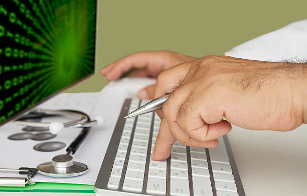 پزشک در حال کار با کامپیوتر و اهمیت حفظ اطلاعات بیماران در سایت