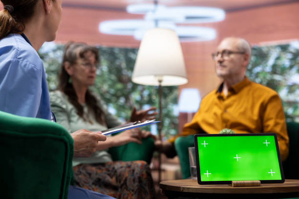 طراحی UX بیماران و وبسایت سلامت مدرن برای مراکز توانبخشی عصبی و جسمی در تبریز: یک مرد و زن مسن در حال گفتگو با پرستار در خانه، با صفحه سبز در پسزمینه، نشان دهنده سهولت دسترسی و ارتباط در تجربه دیجیتال بیماران.