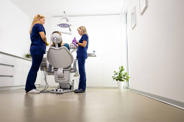 دندانپزشک زن با دستیار در کلینیک دندانپزشکی در حال معاینه بیمار، سئو دندانپزشکی و بهینهسازی وبسایت سلامت