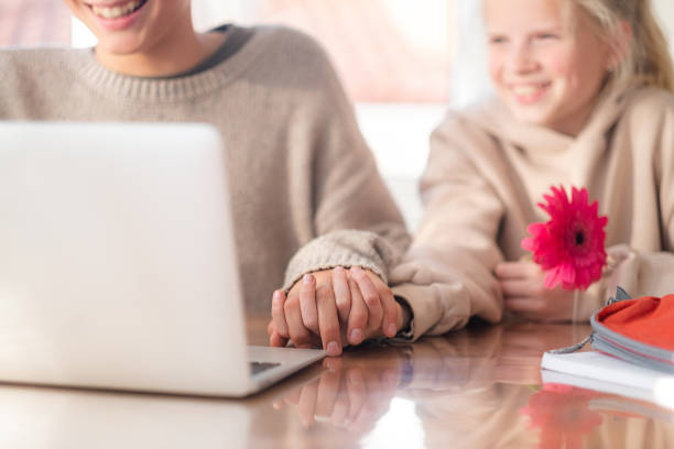 تصویر زوج جوان در حال مطالعه با لپتاپ در خانه، والدین در حال جستجوی وبسایت دندانپزشکی کودکان