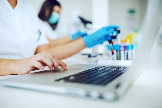 تصویر دستیار آزمایشگاه در حال ورود داده با لپتاپ - مدیریت دادهها در آزمایشگاه تشخیص طبی آنلاین