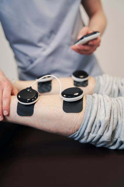 متخصص فیزیوتراپی در حال کار با دستگاه تحریک عضلانی در مرکز فیزیوتراپی تبریز - نوبتدهی فیزیوتراپی، سیستم مدیریت کلینیک