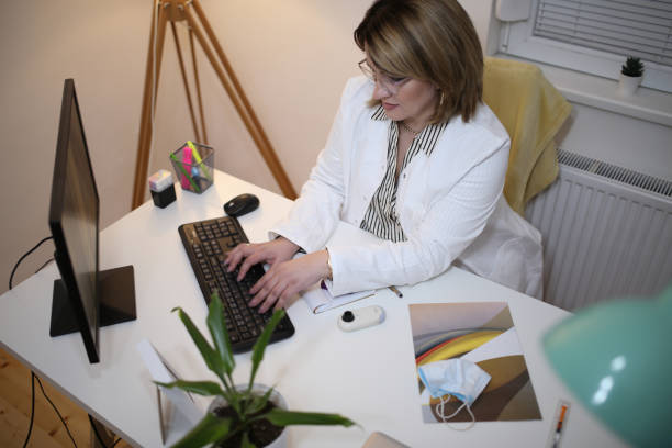 پزشک در حال بررسی سوابق بیماران بر روی کامپیوتر، نمادی از مدیریت داده و سئو برای فوق تخصص زنان