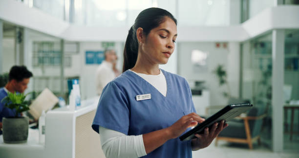 طراحی سایت پزشکی و برندینگ دیجیتال مراکز پزشکی هستهای در مشهد: پرستار در حال کار با تبلت برای پرونده دیجیتال بیماران و ارتقاء تجربه کاربری