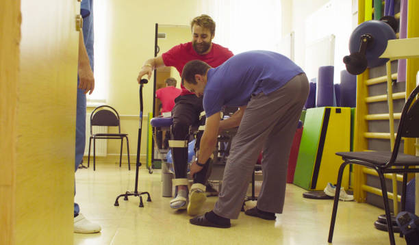 بیمار با ارتز دوپایی آماده راه رفتن با عصا در یک مرکز توانبخشی که از سئو پزشکی و CRM برای جذب بیمار استفاده میکند.