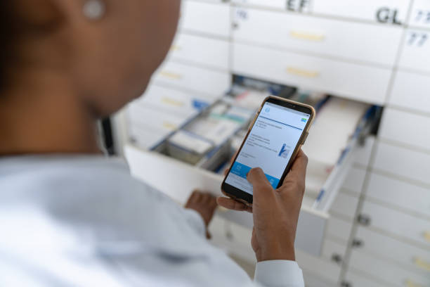 داروسازی در حال خواندن نسخه از تلفن همراه و جستجو برای داروها در داروخانه - پرتال نوبتدهی آنلاین داروخانه