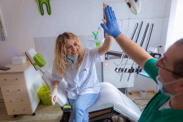 طراحی UX بیماران برای مطب ایمپلنت دندان در مشهد - دندانپزشک و دستیارش در حال تبادل انرژی مثبت و همکاری، افزایش رضایت بیمار دندانپزشکی، بهینهسازی UX کلینیک دندان