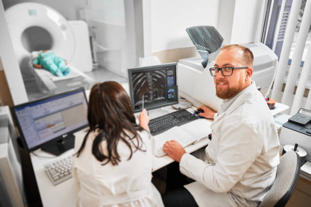 پشتیبانی وبسایتهای درمانی مراکز MRI و CT Scan در رشت: دو پزشک در حال کار با کامپیوتر و بررسی نتایج MRI، پایداری سایت پزشکی