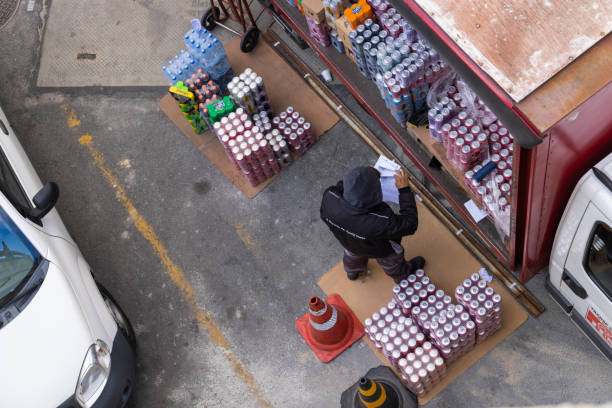 عمدهفروشی نوشیدنیها - مردی در حال بررسی فاکتور محصولات، نشان دهنده خرید و فروش عمده و مدیریت سفارشات در فروشیاب