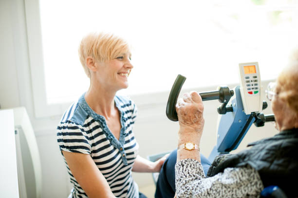 طراحی سایت پزشکی برای کلینیک فیزیوتراپی مشهد: بیمار در حال تمرین روی دوچرخه و کمک فیزیوتراپیست