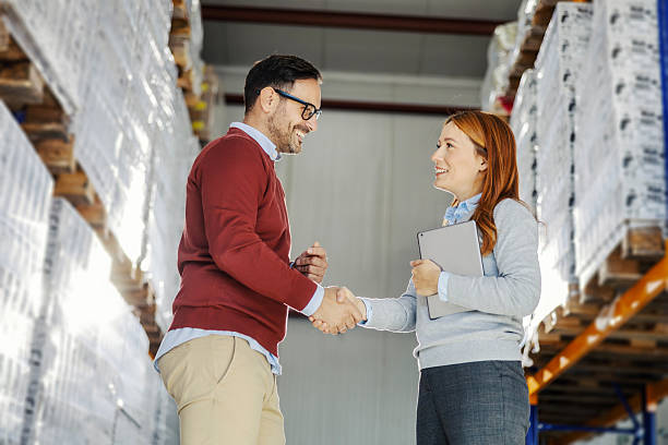 شرکای تجاری در حال دست دادن در یک انبار، صحنه ای از اعتماد و همکاری در فروش‌یاب