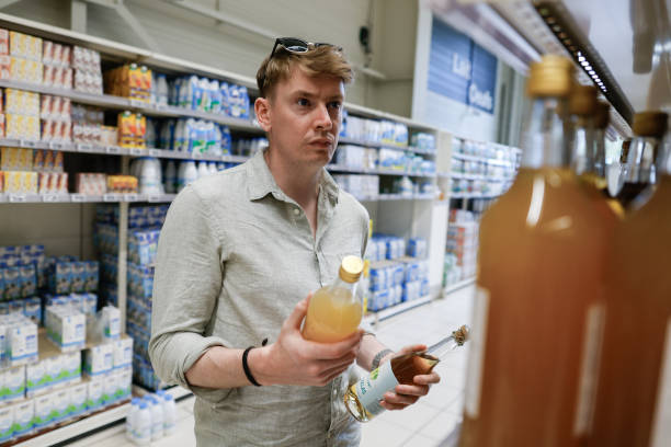 عمدهفروشی نوشیدنیها - مشتری در حال انتخاب نوشیدنی در سوپرمارکت، نتیجه خرید عمده با قیمت رقابتی از فروشیاب