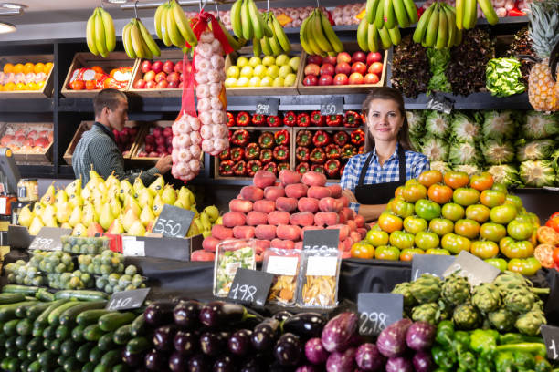 یک فروشنده خانم در حال عرضه میوههای تازه در بازار، نمادی از فروش مستقیم محصولات کشاورزی و عمده فروشی میوه در فروشیاب