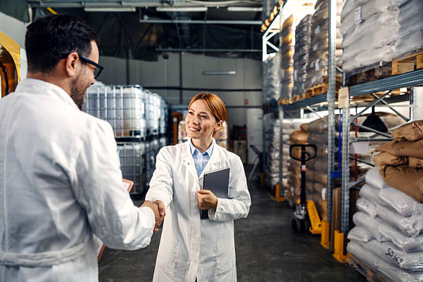 فروش‌یاب، خرید و فروش عمده، آگهی تجاری - کارگران در لباس آزمایشگاه در حال دست دادن در انبار