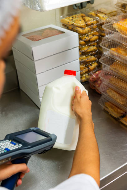 لبنیات عمده و تازه | کارگر سوپرمارکت در حال اسکن شیر، نمایش فرآیند فروش خرده لبنیات پس از خرید عمده از فروش یاب