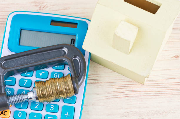 قیمت عمده مصالح ساختمانی، مفهوم وام و تامین مالی مسکن، ماکت خانه و ماشین حساب روی میز چوبی - فروش یاب، کاهش هزینه ساخت و ساز، خرید مستقیم