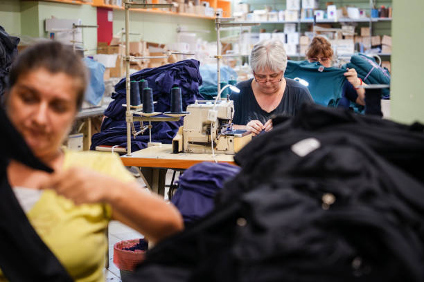 مد، پوشاک و پارچه عمده | کارگران مشغول به کار با ماشین‌های خیاطی در کارخانه نساجی، نمادی از تولیدکنندگان پوشاک و فروش یاب