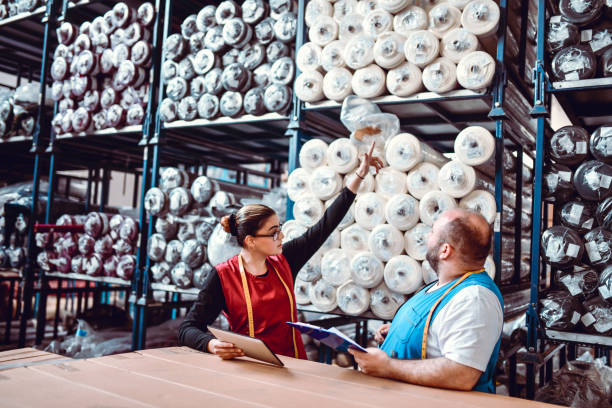 زنی که در انبار کارخانه نساجی به مواد کم کیفیت اشاره می‌کند - فروش یاب، پلتفرم خرید و فروش عمده با آگهی‌های تجاری قابل اعتماد